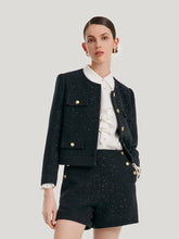 A lady wears a cropped jacket and black shorts.